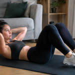 Femme effectuant crunch jambes repliees sur tapis noir